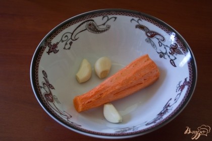 Очистите морковь и чеснок. Нарежьте на небольшие кусочки и нашпигуйте ими мясо.