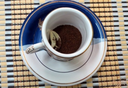 В пустую чашечку насыпаем свежемолотый кофе. На кофе отправляем лепесток чеснока.