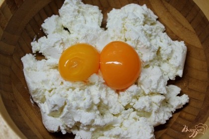 В творог добавляем 2 яичных желтка и перемешиваем.