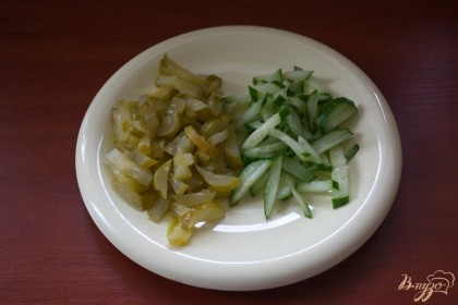 Для приготовления салата нужно нарезать соленый и свежий огурчики соломкой.