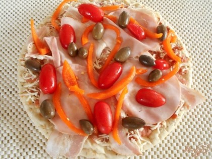 Помидоры -черри разрезаем на половинки, выкладываем их на пиццу, также выкладываем и оливки.