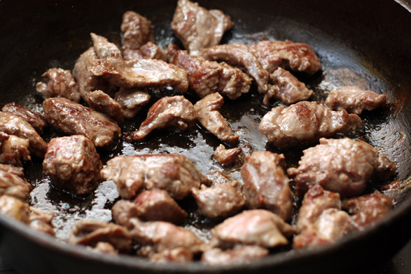 Когда мясо зарумянится со всех сторон, переложите его в толстостенную кастрюлю. Посолите и добавьте специи.