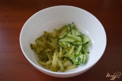 Для приготовления салата соленый и свежий огурцы нарезаем соломкой. Перекладываем в салатник.