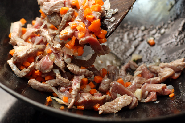 Добавьте морковь и мясо. Готовьте, помешивая, до тех пор, пока мясо не потеряет розовый оттенок.