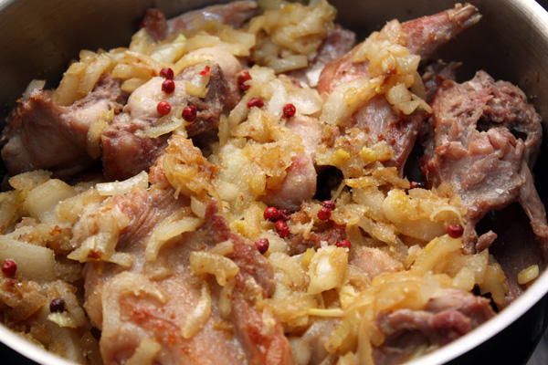Мясо посолите, сверху выложите лук и добавьте горошины розового перца. 