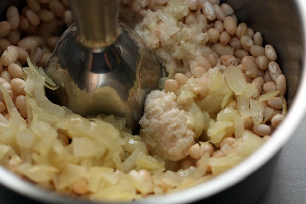В сваренную фасоль добавьте лук и хорошенько измельчите смесь блендером.