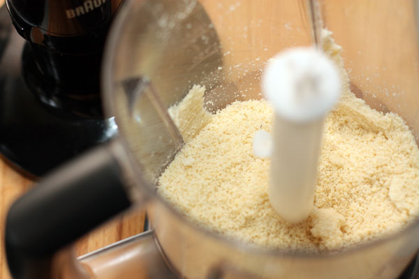 Измельчите орехи до состояния мелкой крошки. Если в качестве ароматизатора вы используете горький миндаль, его тоже измельчите.