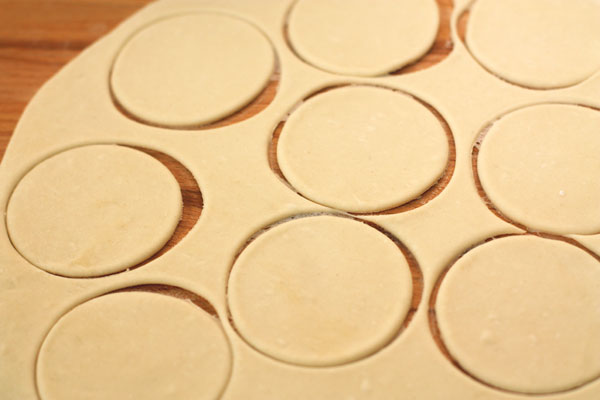 Тесто (отрезая частями) раскатывайте толщиной 1 мм и с помощью стакана вырезайте круги диаметром 8-9 см.
