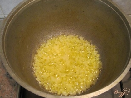 В толстостенной кастрюле растопить сливочное масло. Добавить лук и обжарить до золотистого цвета.
