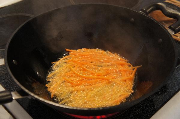 В воке разогреть растительное масло на сильном огне и положить туда морковь.