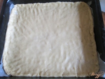 Выкладываем на противень пекарскую бумагу  и распределяем на нем большую часть теста. Я раскатываю тесто сначала ладонями, потом пальцами. Слой должен быть примерно полсантиметра.