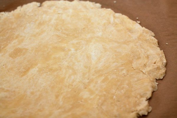 Добавьте ликер, ванильный сахар и 2-3 ст.л. ледяной воды. Сделайте такое тесто, чтобы из него можно было слепить шар.  Раскатайте тесто в круглый пласт толщиной около 0,5 см. Диаметр пласта должен быть на 3-4 см больше, чем диаметр формы, чтобы потом можно было сделать бортики.  Раскатанное тесто уберите в холодильник на полчаса.
