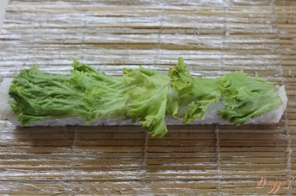 Закрутить начинку в квадратный ролл, хорошо зажать и положить сверху лист салата, прижать его к рису с помощью бамбукового коврика.