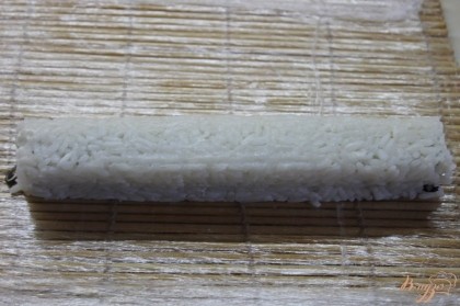С помощью бамбукового коврика скрутить ролл и хорошо зажать.