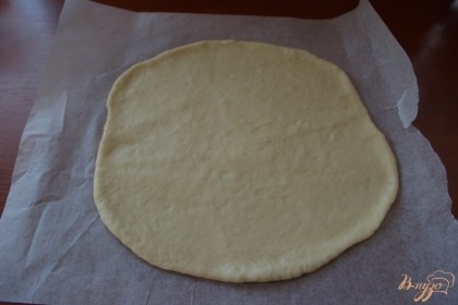 Разделите тесто на 2 части. Одну раскатайте в круг на бумаге для выпечки.