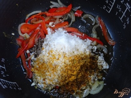 После этого откройте крышку, перемешайте овощи и добавьте промытый рис. Используйте специи по вкусу – соль, перец, куркума и смесь для плова.