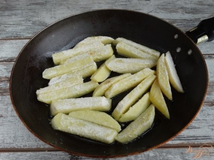 Картофель чистим и режем крупной соломкой. Ополаскиваем ее холодной водой, высушиваем при помощи полотенца и обваливаем в муке с солью. Жарим картофельные дольки на растительном масле.