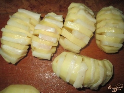  Нарезать картофель пластинками по 7 мм в толщину, не дорезая их до конца. Получится гармошка. Между пластинками картофеля вставить кусочки сала.