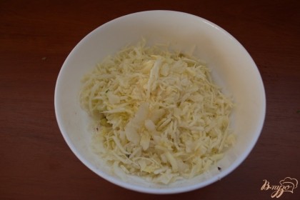 Нашинкуйте очень тонко белокочанную капусту. Посыпьте ее солью и перцем. Помните руками и переложите в салатник.