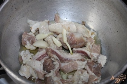 Свинину нарезать крупным кубиком и обжарить в горячем сотейнике с добавлением растительного масла и чеснока.
