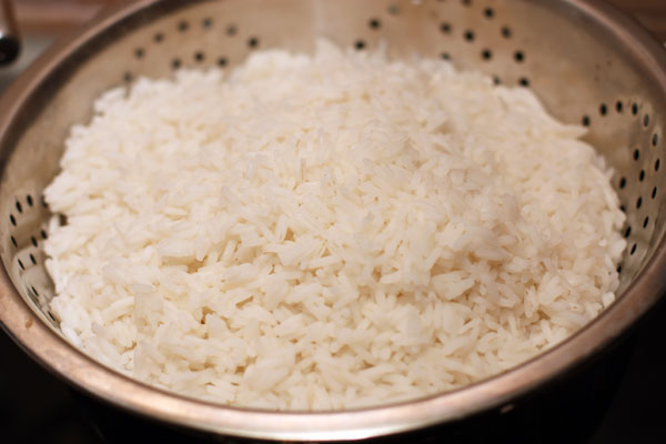 Сразу поставьте варить рис в подсоленной воде. Когда он будет готов, откиньте на дуршлаг. Подойдут любые сорта длиннозерного риса.