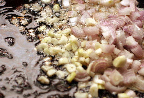 На жире, оставшемся от жарки свинины слегка обжарьте (1-2 минуты) мелко нарезанный шалот и измельченный чеснок, затем добавьте очищенный и натертый на мелкой терке корень имбиря.