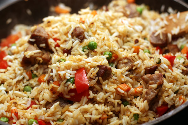 Когда овощи станут мягкими, верните в сковороду мясо и положите рис. Посолите, перемешайте и готовьте еще 5-7 минут.