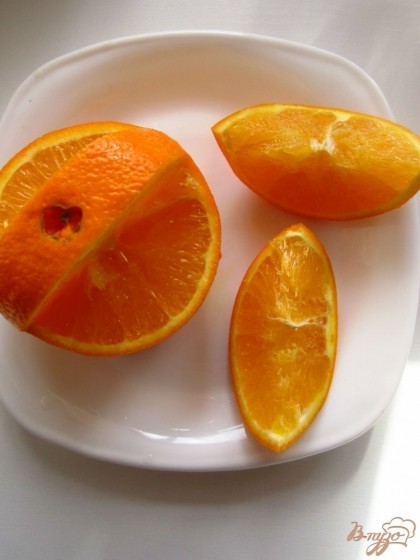 Возьмите апельсин, помойте его. Сначала вырежем ручку апельсиновой корзины. Отмеряйте середину ручки, ее ширина 2см, и отрежьте две дольки апельсины как показано на фото.