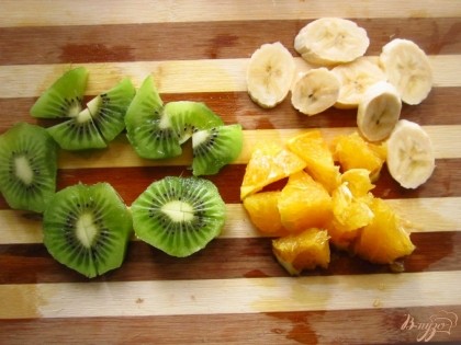 Нарежьте фрукты на кусочки, а именно банан, киви, апельсин.