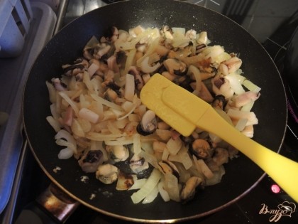 Пока варятся рис и картофель, добавляем к луку морепродукты и обжариваем их немного времени.