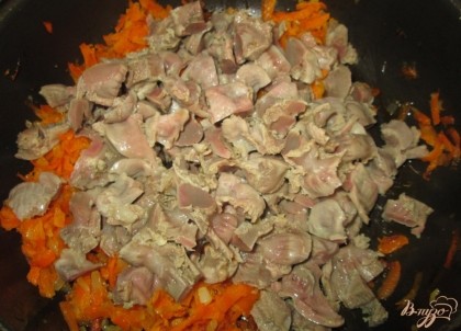 Добавить к моркови и луку, отваренные в подсоленной воде и порезанные, куриные желудки. Жарить около 10-15 минут, помешивая.