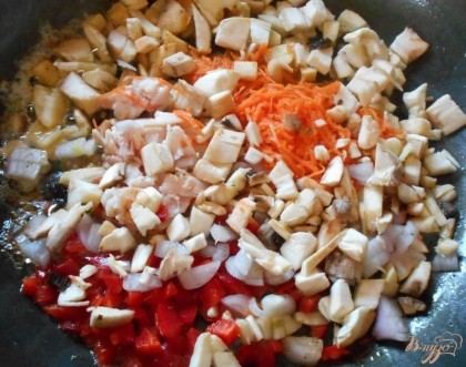 Для начала приготовим начинку для грибов. Для этого натрем морковь на терке, перец, лук и перец болгарский нарежем очень мелким кубиком. Обжарим овощи на сливочном масле.