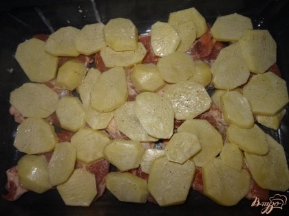 На верх мяса выложить половину картофеля. Распределить по всему противню.