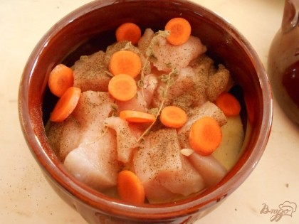 На картофель выкладываем кусочки куриного филе, кружочки моркови и веточку сушеного тимьяна.