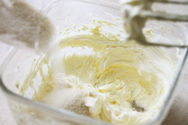 Сливочное масло выложите из холодильника заранее, чтобы оно было мягким. Взбейте его миксером до белого цвета, затем добавьте сахар и продолжайте растирать вместе ещё несколько минут. Сахар лучше брать мелкий.
