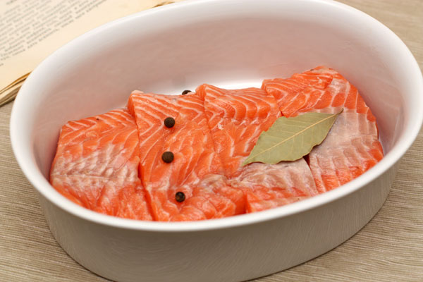 Филе рыбы нарежьте порционными кусочками, сложите в форму для запекания. Добавьте перец и лавровый лист.