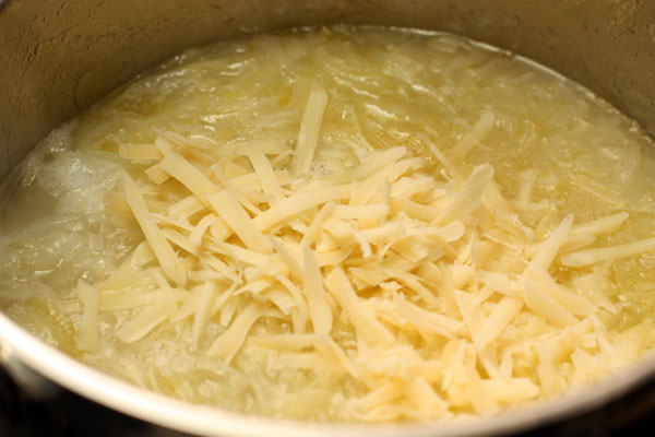 Готовьте 5 минут, потом налейте бульон или воду, доведите до кипения и насыпьте тертый сыр. Размешайте, чтобы сыр растворился и посолите по вкусу.