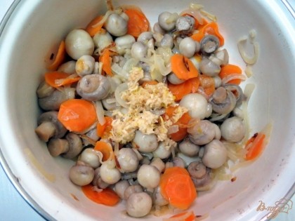 В миску с грибами, высыпьте пассерованные лук и морковь, выдавленный через пресс чеснок, специи, уксус, зелень.