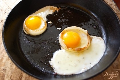 Разделите яйца на белки и желтки. В сковородку кладем по 1 колечку лука. В дырочку помещаем желток и пустоты заполняем белком. Жарим с одной стороны.