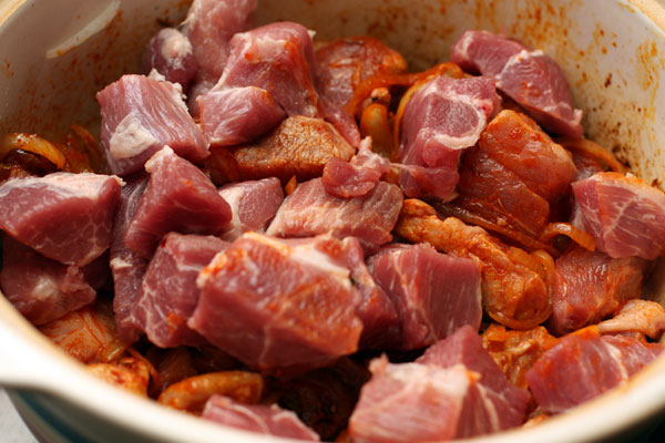У мяса срежьте лишний жир, нарежьте его кубиками около 3 см и добавьте к луку. Слегка обжарьте со всех сторон. 