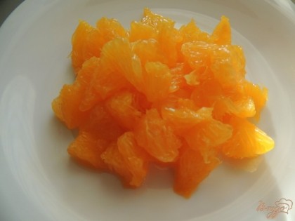 Апельсин разделяем на дольки, освобождаем он белых плёнок и разделяем на небольшие кусочки.