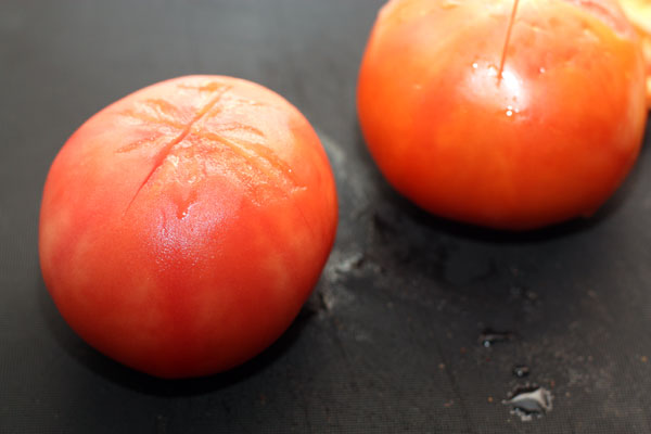На помидорах сделайте неглубокий крестообразный надрез и опустите в кипяток на минуту. После этого снимите кожицу.