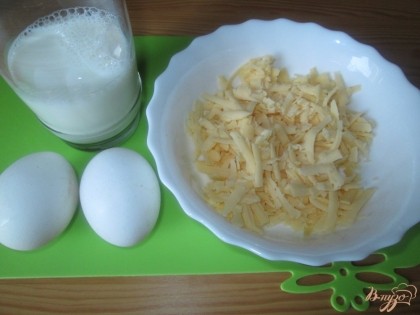 Теперь приготовим заливку. В блюдо разбить 2 куриных яйца, влить 0,5 стакана молока и натереть сыр.
