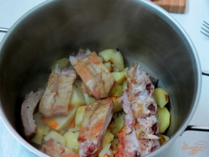 Начинаем перекладывать в кастрюлю картофель с луком и морковью. На них выкладываем копчёные рёбра.