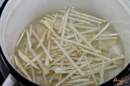 В горячую воду опустить сельдерей, через 5 минут добавить картофель.